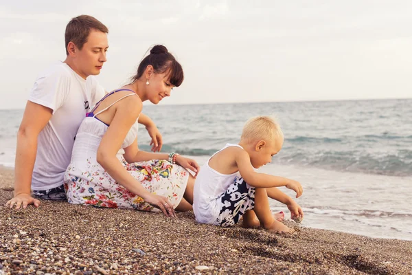 Family sitting on a  sand seashore near sea looking at each othe