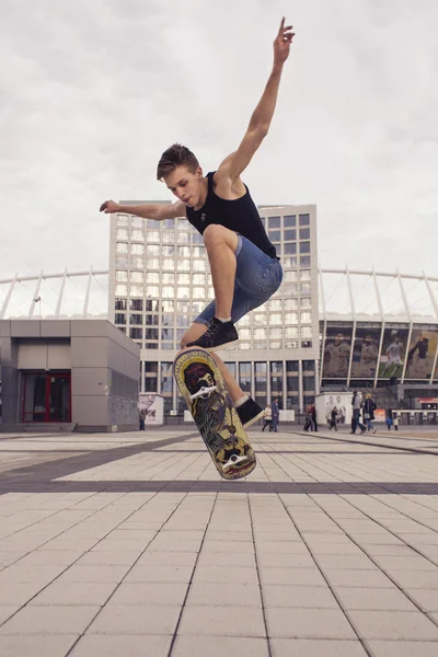 Young blonde guy jumping on skateboard in casual outfit in the u