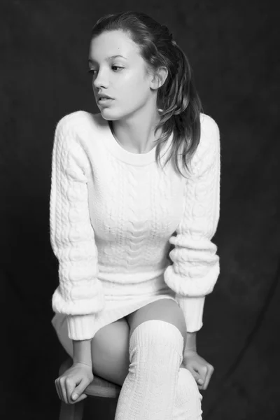 Beautiful woman in white sweater on black background. Black and