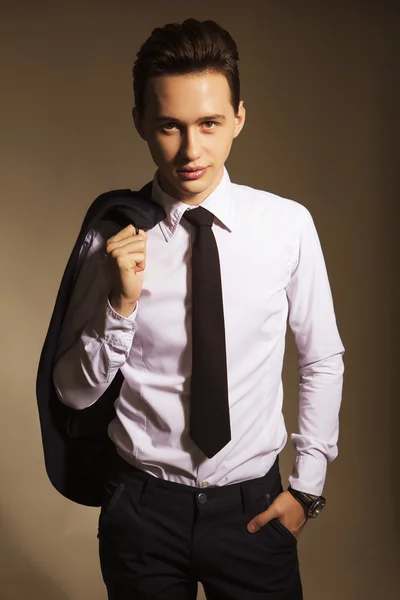 Young handsome brunette macho businessman in black suit and tie.