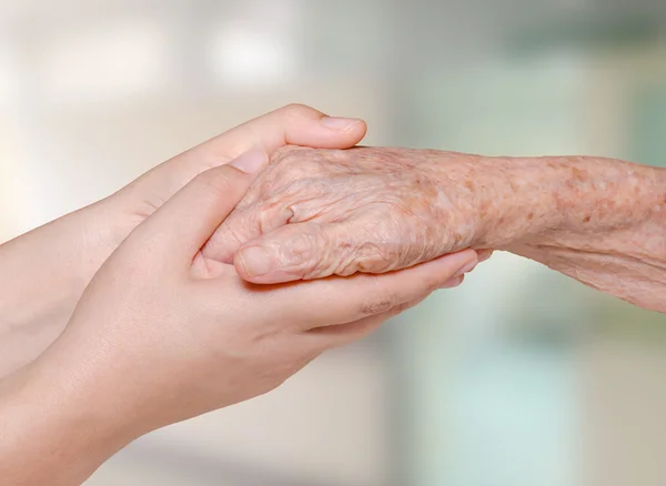 Nurse holding old patient hand in hospital