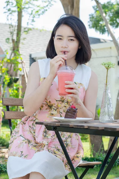 Woman drinks strawberry smoothie at cafe
