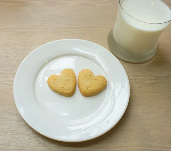 Heart cookies in white plate and a glass of milk