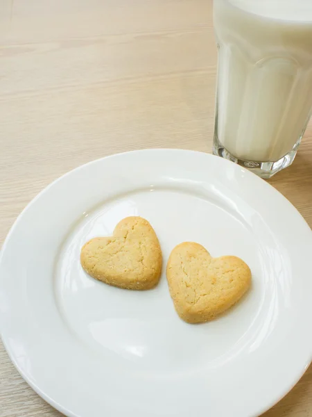 Heart cookies in white plate and a glass of milk