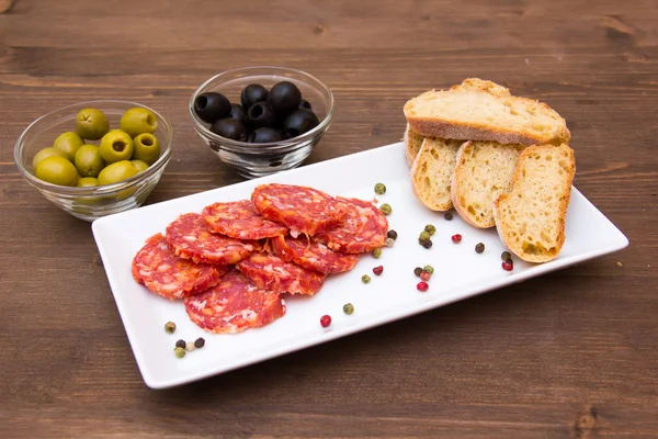 Antipasto of salami and olives on wood