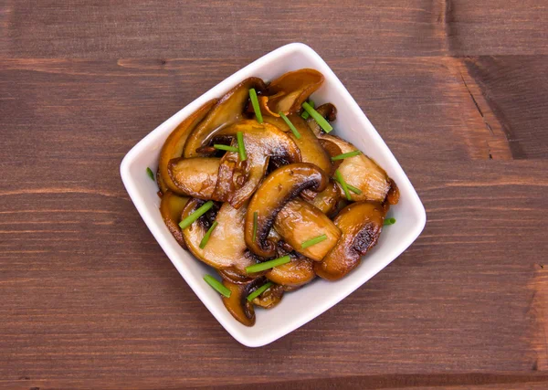 Baked mushrooms on square bowl on top of wood