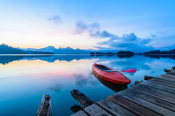 Canoe floating on the calm water under amazing sunrise