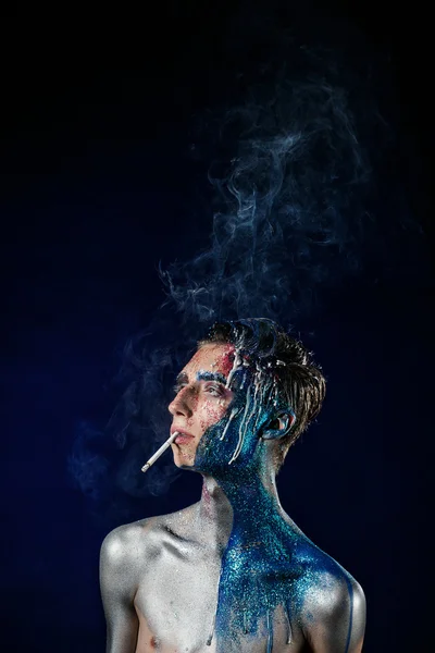 Crazy young man with face art smoking and enjoying. Freak person