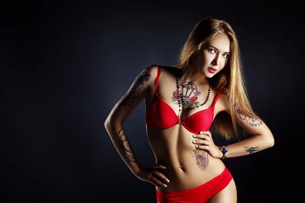 Pretty girl with tattoo posing in red lingerie