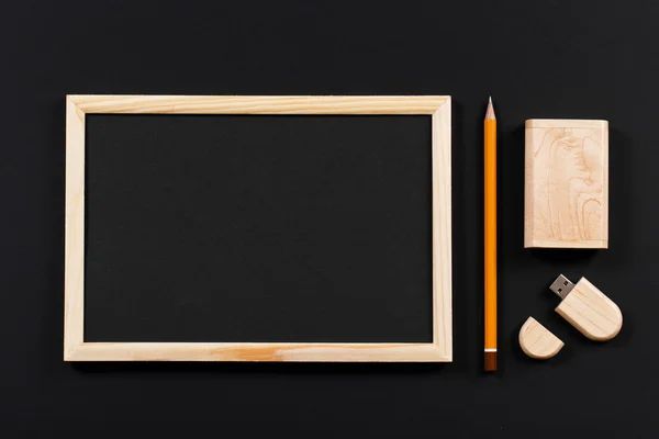 Wooden frame with black field and pencil and usb flash drive in