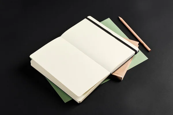 Open blank notepad with empty white pages laying above book with
