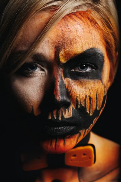 Halloween portrait of body art pumpkin girl with pumpkin bowtie on black background. Real greasepaint and face art makeup. Straight look and black lips