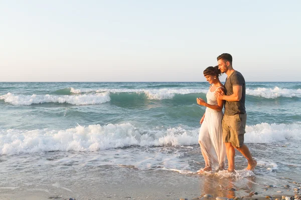 Young couple enjoys walking on a hazy beach at dusk.