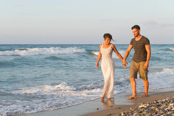 Young couple enjoys walking on a hazy beach at dusk.