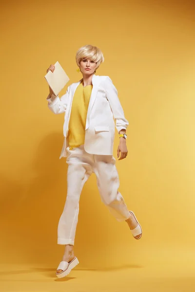 Young girl having fun and jumping. Smiling girl with yellow background wearing fashion clothes