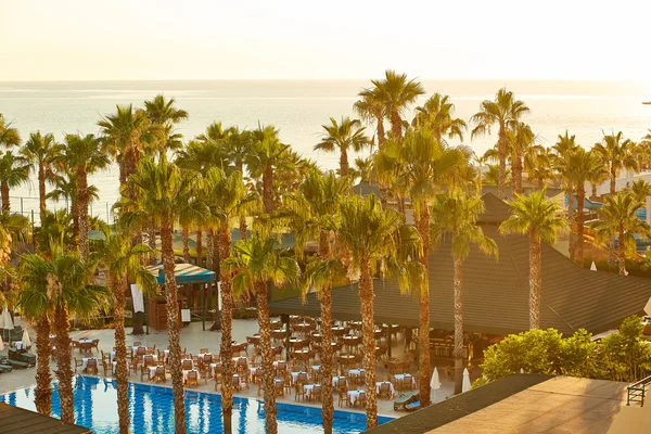 Beautiful sunrise on sea resort with palms and swimming pool