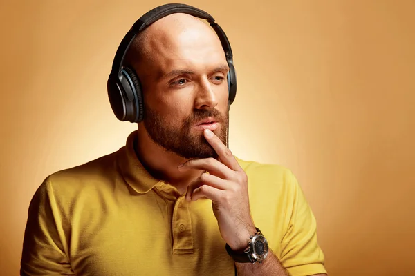 Handsome young bald man with thinking face and earphones