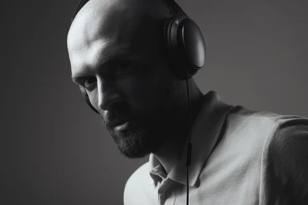 Black and white portrait of young bald man with earphones