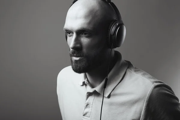 Closeup portrait in black and white of handsome bald man with earphones