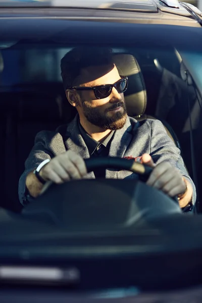 Attractive elegant man in sunglasses in good car