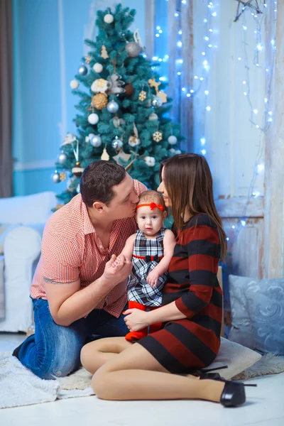 Family with Kid kissing. Happy Smiling Parents and Child at Home Celebrating New Year. Christmas scene