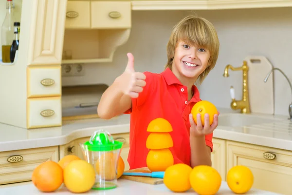 Child with oranges. Boy squeez fresh orange juice and showing thumbs up