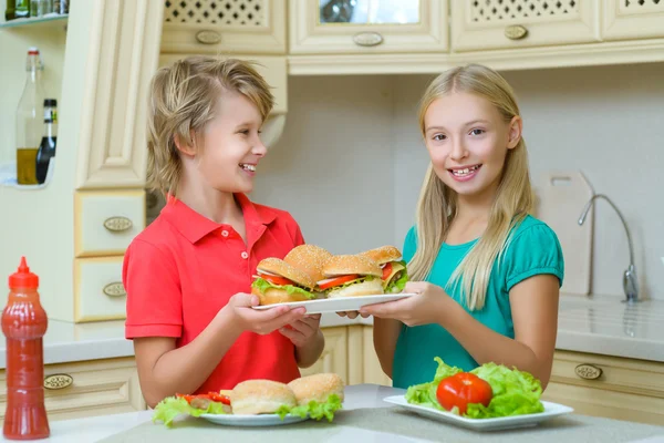 Smiling happy boy and girl holding homemade hamburgers or sandwiches