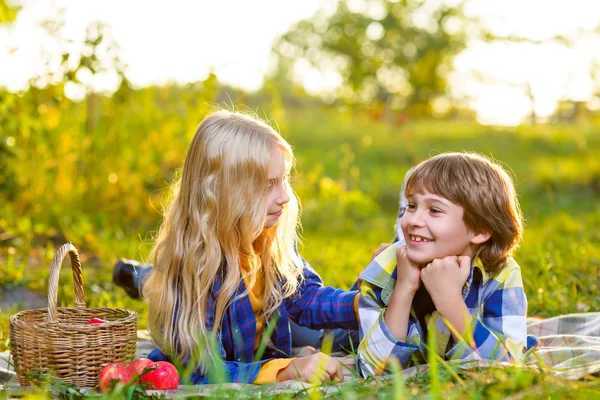 Happy kids eating fruits from picnic basket outdoor. romantic or first love concept
