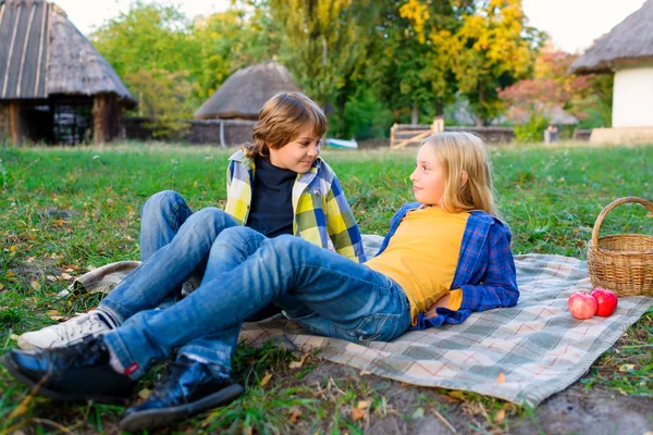 Happy smiling boy and girl lying together on rug. picnic in park concept