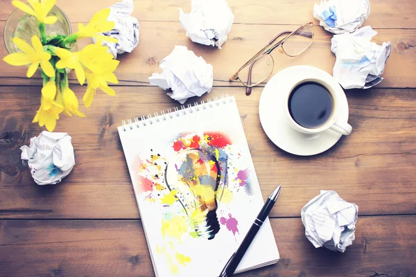 Coffee, pen, notepad, papers, glasses and flower on table