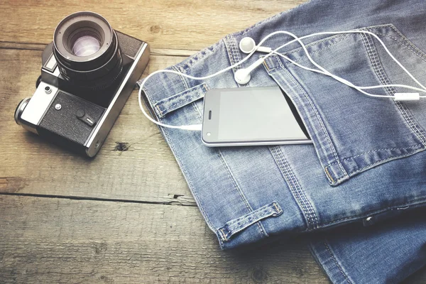 Camera, phone and earphone on jeans