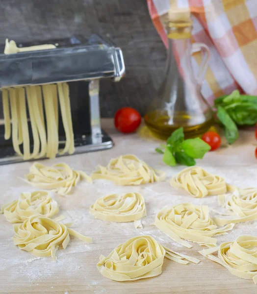 Fresh homemade pasta machine pasta, basil, tomatoes on a wooden
