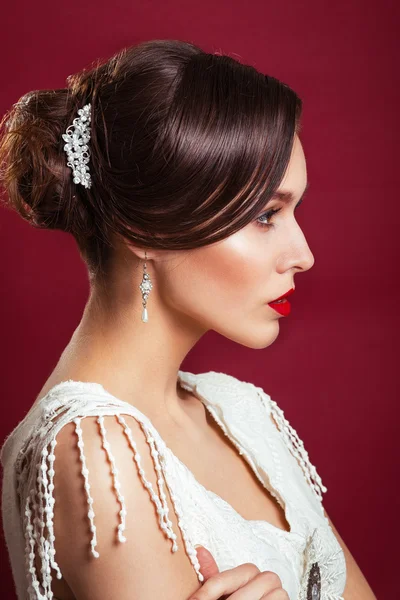 Portrait of the beautiful young girl in an image of the bride with ornament in hair.Beautiful young model with red lips.Woman with Perfect Makeup. Red Lips . Glamorous Woman.