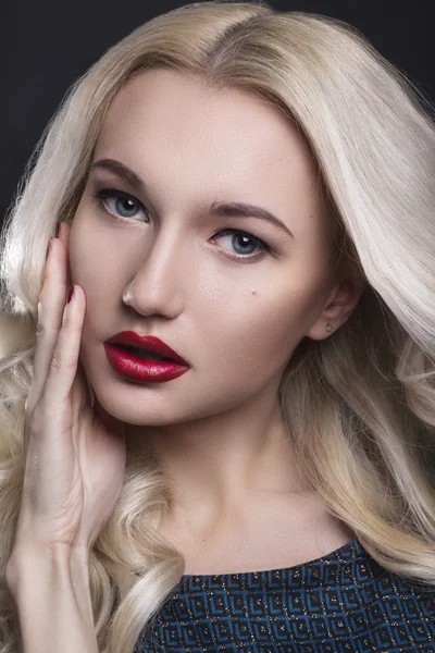 Beauty Woman with Perfect Makeup. Beautiful Professional Holiday Make-up. Red Lips and Nails. Beauty Girl\'s Face isolated on Black background. Glamorous Woman. Blonde woman with perfect curly hair