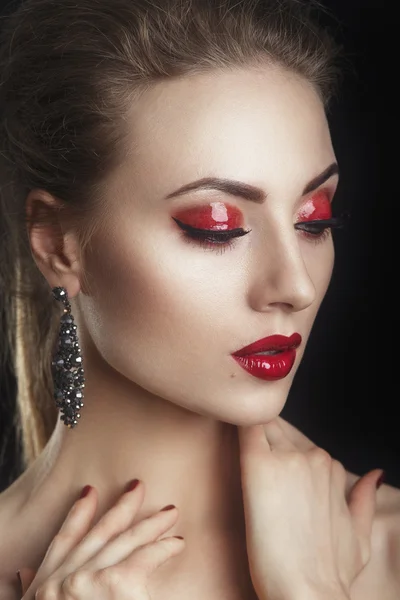 Beautiful elegant young model with red lips and color evening make-up.Woman Face on dark background.Picture taken in the studio.High fashion look.glamor closeup portrait of sexy stylish brunette