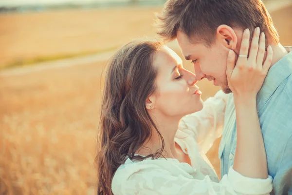 Young couple in love outdoor. Stunning sensual outdoor portrait of young stylish fashion couple posing in summer in field. Happy Smiling Couple in love. They are smiling and looking at each other