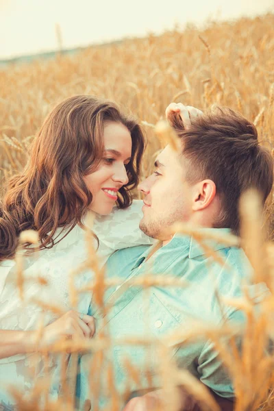 Young couple in love outdoor. Stunning sensual outdoor portrait of young stylish fashion couple posing in summer in field. Happy Smiling Couple in love. They are smiling and looking at each other