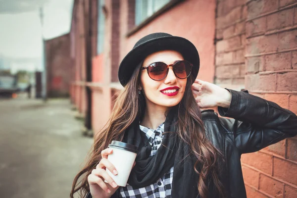 Trendy woman in sunglasses with drinkoutdoor. Young  woman in sunglasses in the street and holding cup of coffee