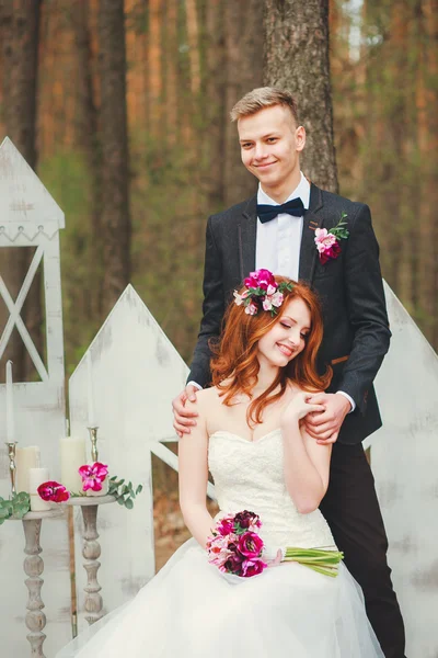 Wedding shot of bride and groom in park. Wedding couple just married with bridal bouquet. Stylish happy smiling newlyweds on outdoor wedding ceremony