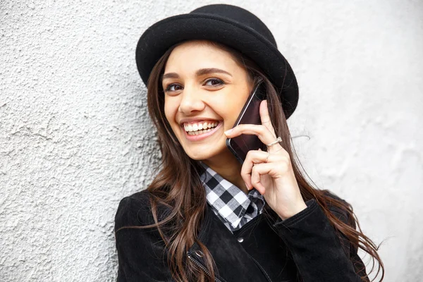 Young pretty girl in hat using smartphone.Woman using smart phone to make a call in the street