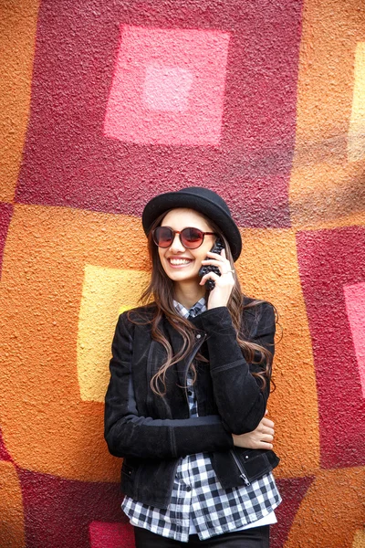 Young pretty girl in hat using smartphone.Woman using smart phone to make a call in the street