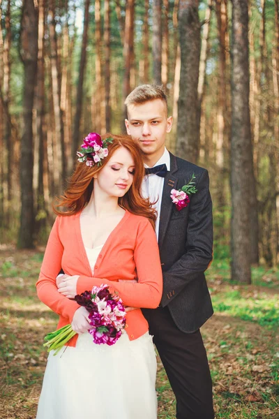 Wedding shot of bride and groom in park. Wedding couple just married with bridal bouquet. Stylish happy smiling newlyweds on outdoor wedding ceremony. Young couple in love outdoor.