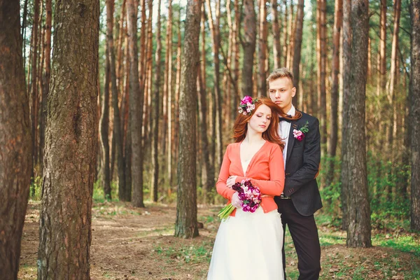 Wedding shot of bride and groom in park. Wedding couple just married with bridal bouquet. Stylish happy smiling newlyweds on outdoor wedding ceremony. Young couple in love outdoor.