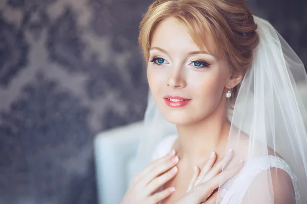 Beautiful young bride with wedding makeup and hairstyle in bedroom.Beautiful bride portrait with veil over her face. Closeup portrait of young gorgeous bride. Wedding.