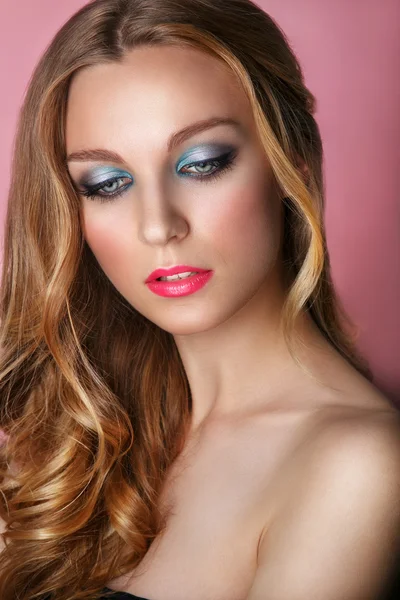 Beauty Model Woman Face on pink shiny background. Perfect Skin. Professional Make-up.Blue eyes and pink lips.