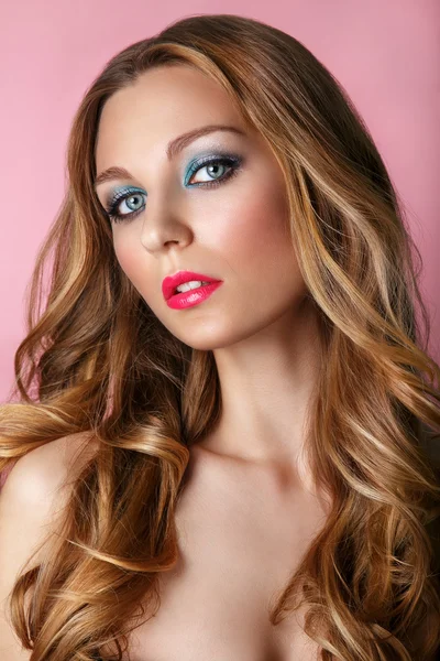 Beauty Model Woman Face on pink shiny background. Perfect Skin. Professional Make-up.Blue eyes and pink lips.