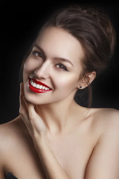 Beautiful smiling young model with red lips and red manicure on black background. Happy model girl