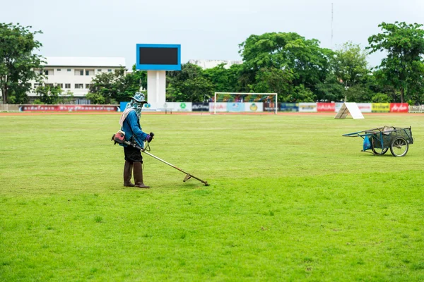 Worker mowing the lawn at soccer stadium.