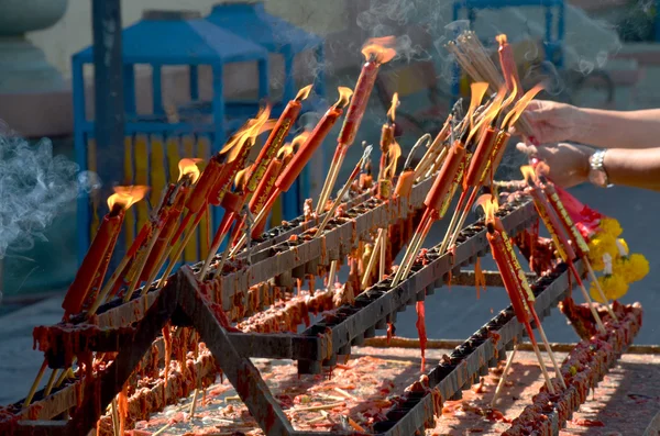 People burning incense and red candle