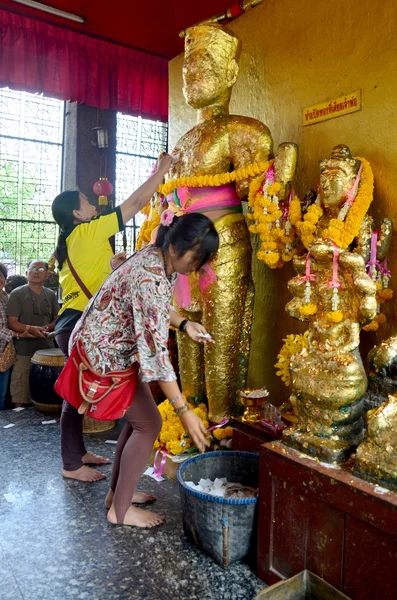 Thai Woman glid cover angel statue with gold leaf at Phra Kal Sh